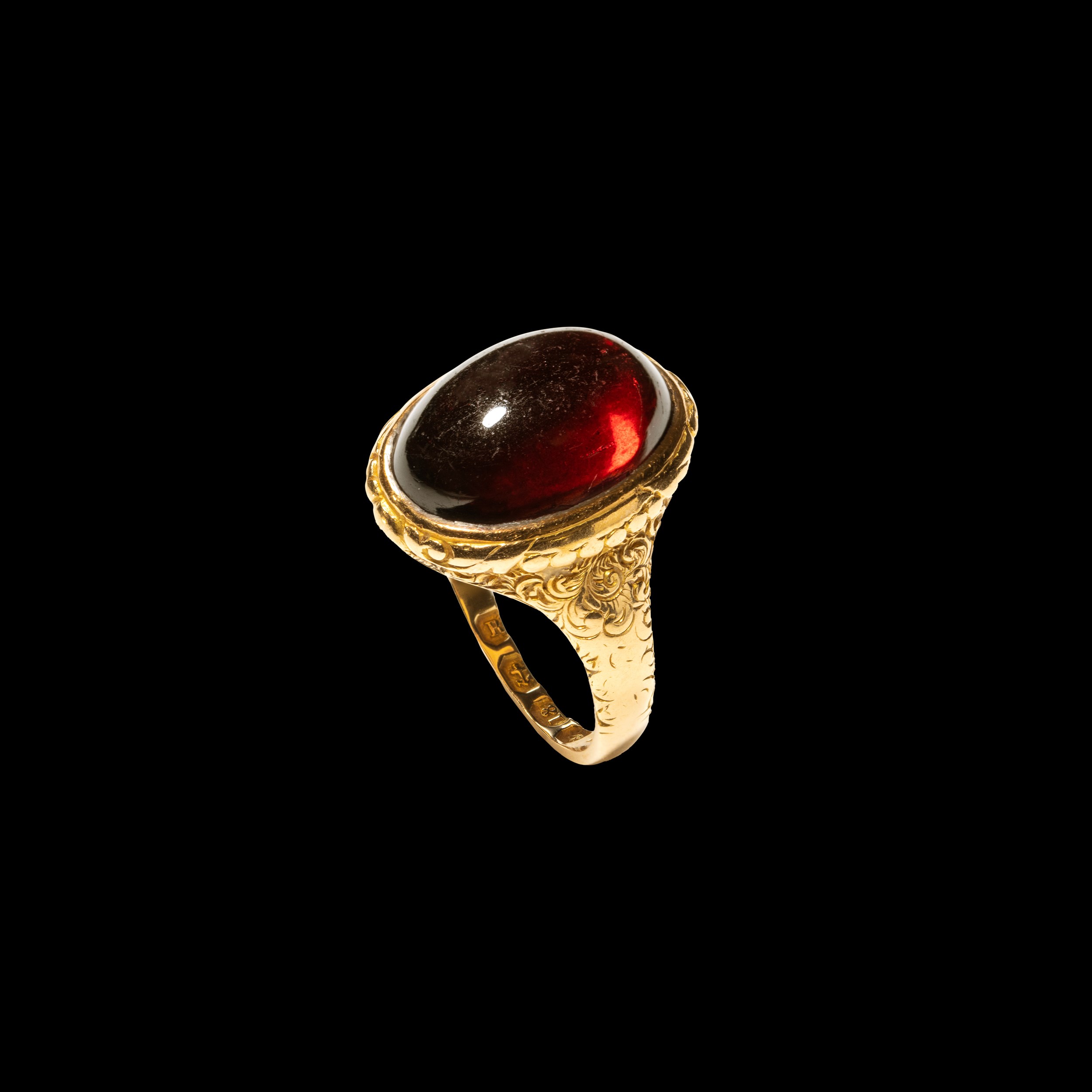 A Victorian chiseled gold ring with a large cabochon garnet. 